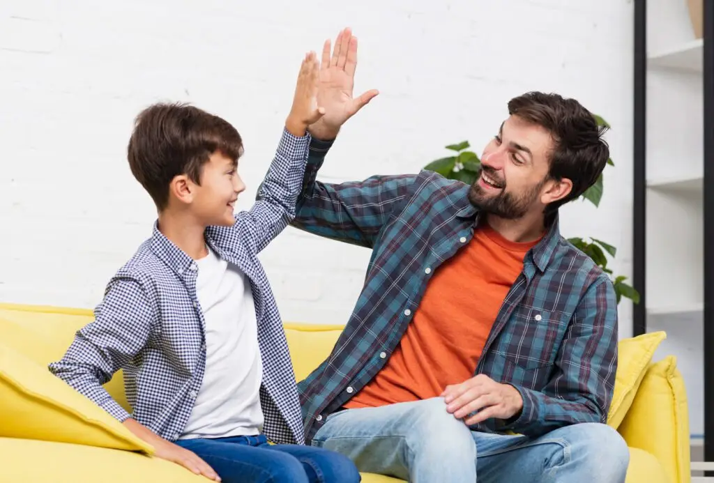 Padre e hijo chocan sus manos. Señal de que su comunicación es fluida. Saben comunicarse.