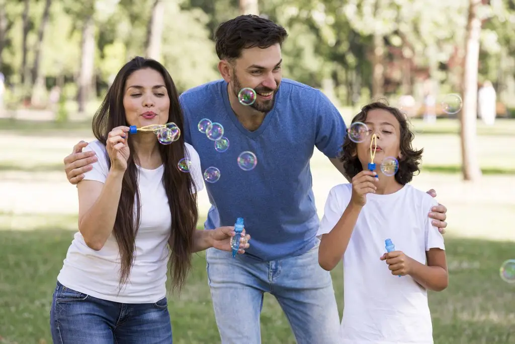 papa y mamá juegan con su hijo. están generando burbujas de jabón